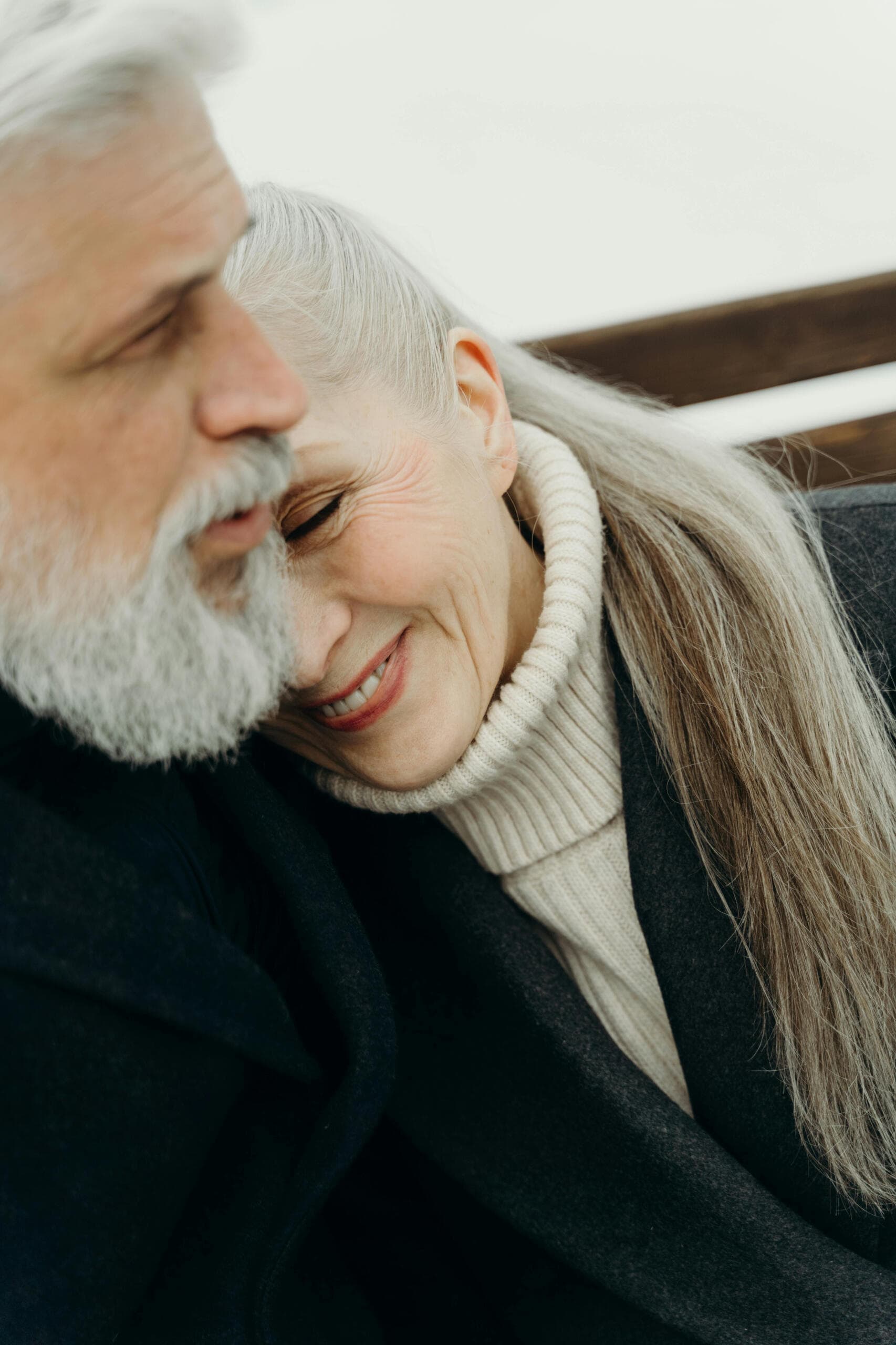 An older couple sharing a quiet, affectionate moment, the woman resting her head against the man's shoulder.